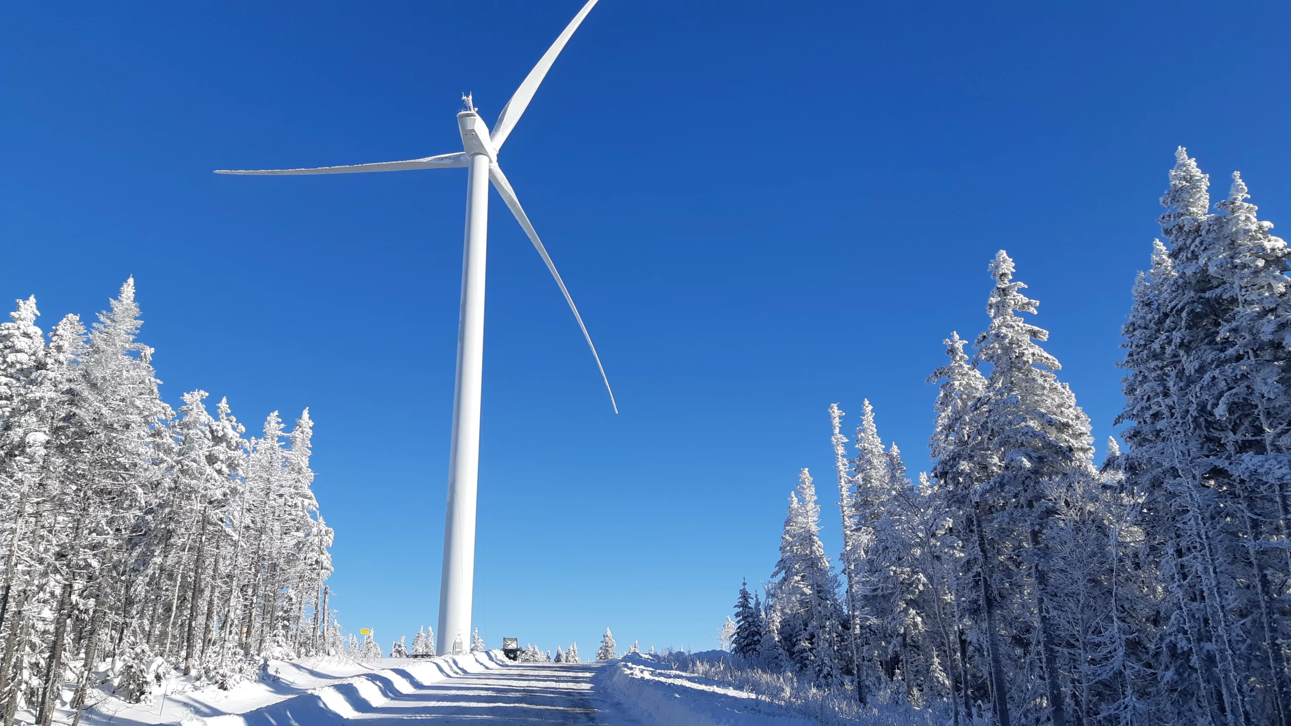 White wind turbine in snowy conditions under a blue sky, 2