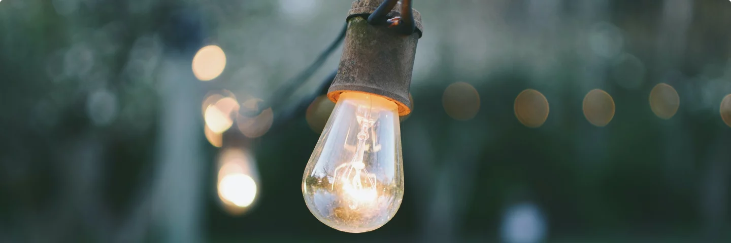 Close-up of a hanging lightbulb glowing outdoors at dusk