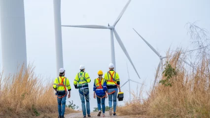 Wind farm employees in a field of wind turbines, 2